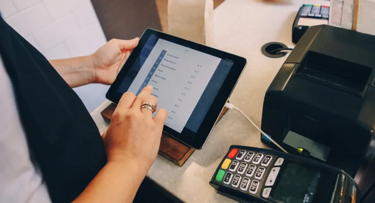 Mobile repair shop employee using tablet and POS terminal for customer transaction